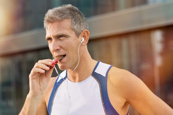 Portrait Of Fitness Mature Man Eating A Energy Bar Of Chocolate